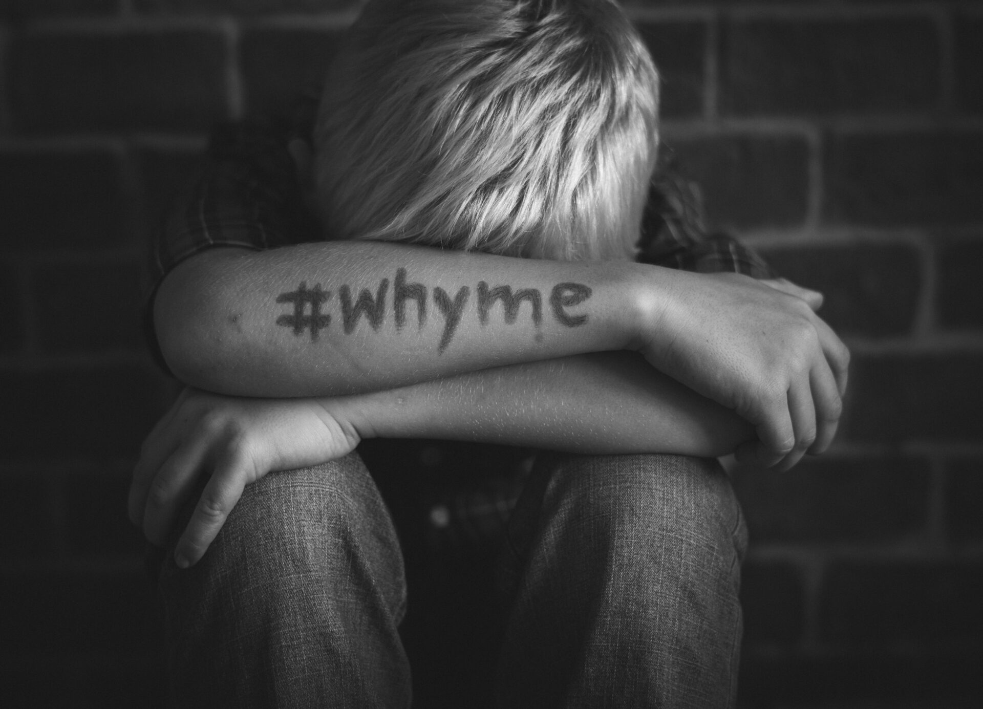 Boy with hashtag why me written on his arm